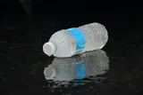 A sealed bottle of water on a dark surface.