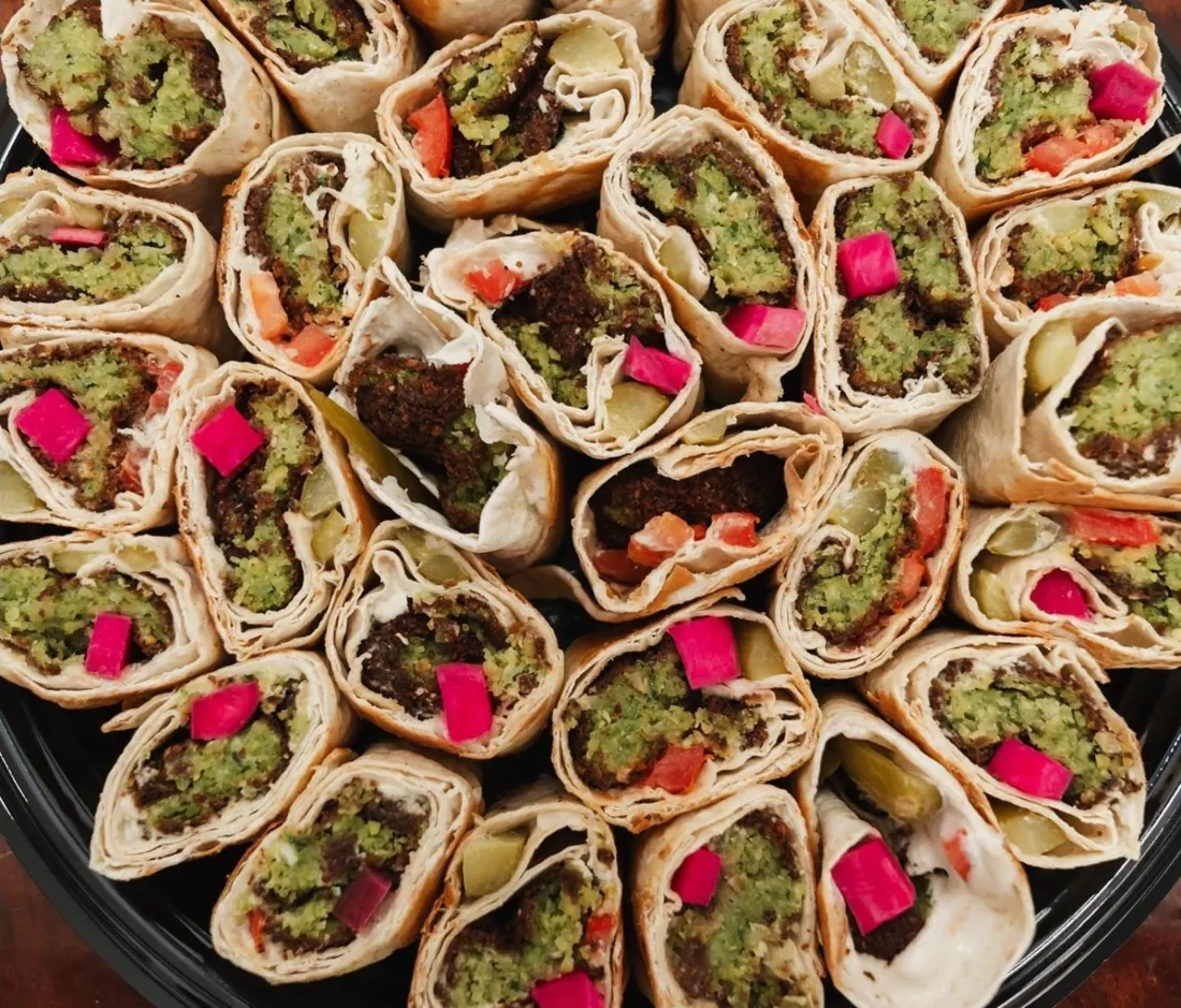 Sliced falafel wraps with vegetables arranged on a catering platter.