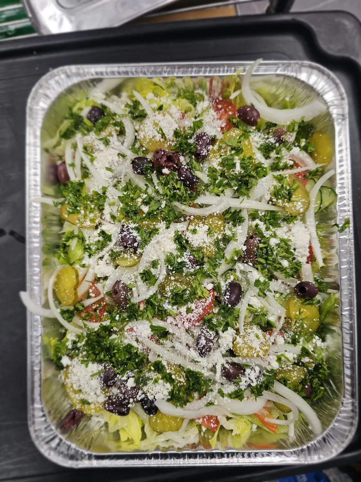 Greek salad in a foil tray from the Pita Lite Eastgate Square Hamilton meeting order.