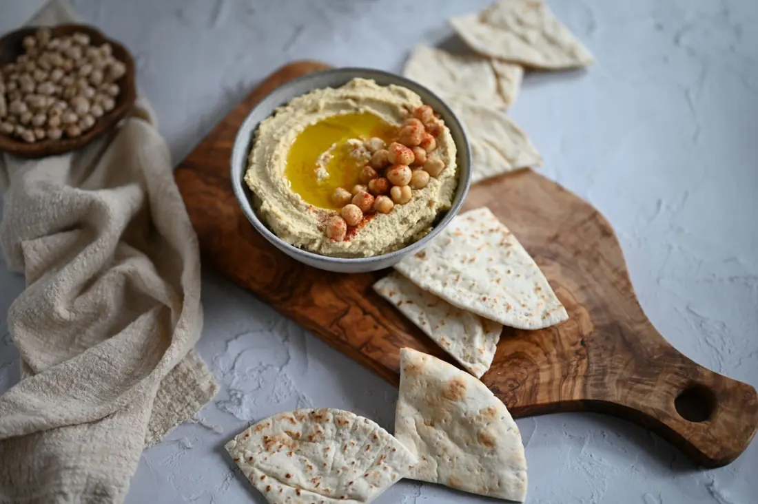 Bowl of hummus with chickpeas, olive oil and pita bread.
