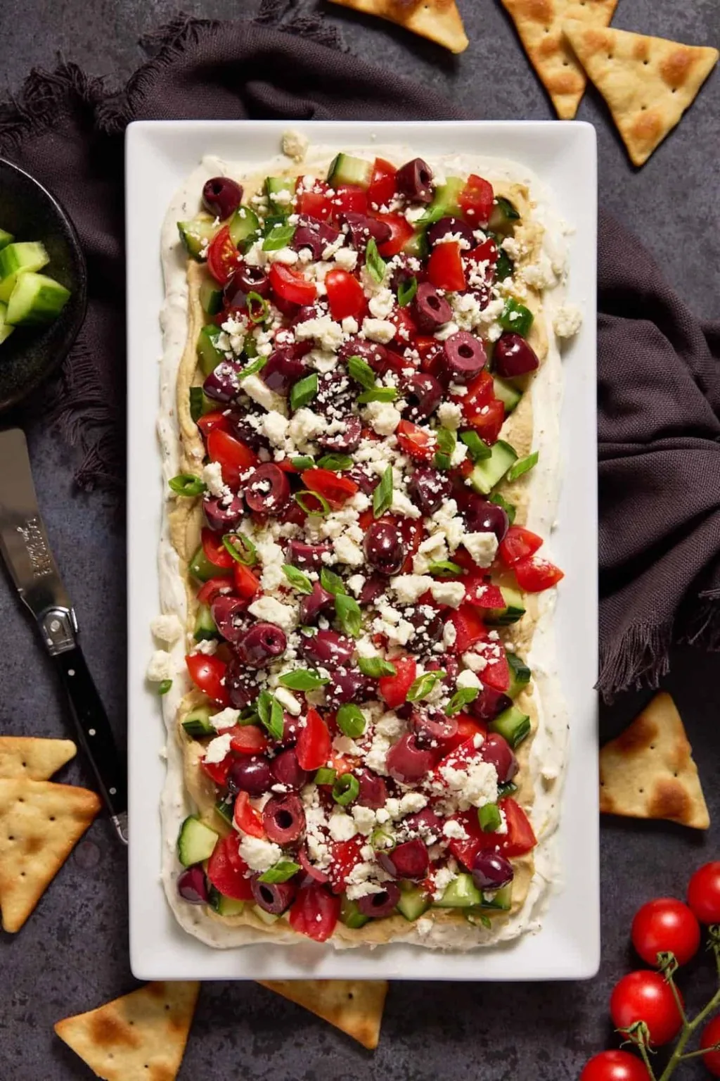 Seven-layer dip topped with tomatoes, olives, cucumber and feta, served with pita chips.